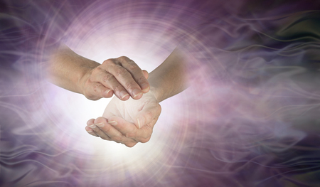 Channeling vortex spiral between hands - female cupped hands with white vortex energy between on a wide pink purple spiralling light burst background with copy spaceの写真素材