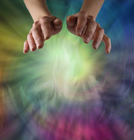 Sensing Chi Healing Energy - female hands hovering over a wispy spiral of multicoloured ethereal energy  with plenty of copy spaceの写真素材