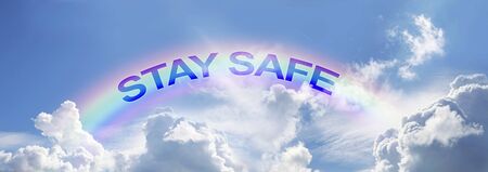 Stay Safe arcing rainbow campaign background - wide blue sky with clouds and rainbow and the words STAY SAFE matching the arc of the rainbow with copy spaceの写真素材