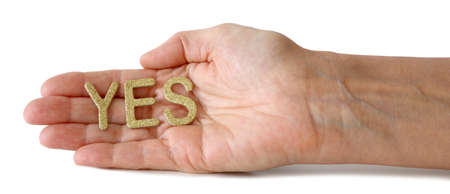 Just say YES - female hand open flat with the word YES in gold glitter laid across isolated on a...
