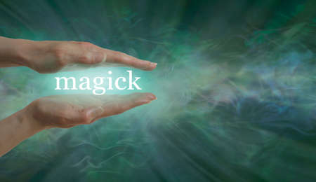 Healing Magick concept background message board - female parallel hands with the word MAGICK between against an outward flowing green energy field background with copy spaceの写真素材