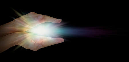 The healing hands of a Lightworker - Female parallel hands against pitch black background with a...