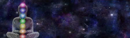Cosmic Buddha Chakra Meditation Message banner - lotus position seated buddha with the seven chakras laid over against a wide dark blue night sky deep space background with space for copyの写真素材