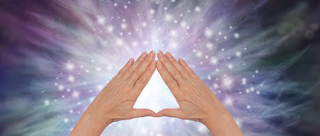 The triangle is a stunning healing tool  - female hands making a triangle against a wide sparkling...