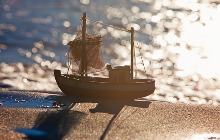 The little toy boat stands on sandy beachの写真素材