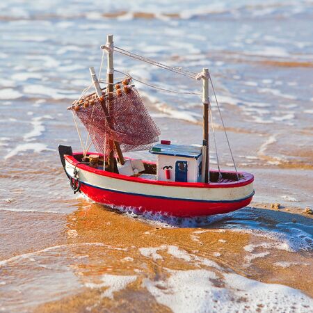 The little toy boat stands on sandy beachの写真素材