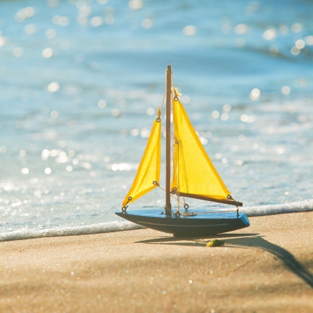 The little toy boat stands on sandy beachの写真素材
