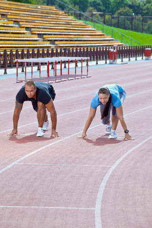 Man and woman on the starting line at the stadiumの写真素材