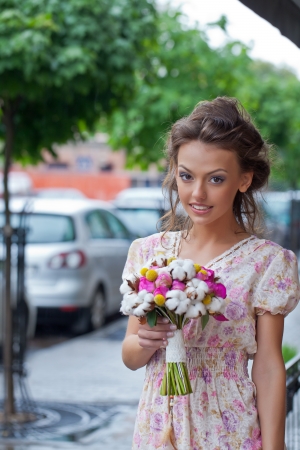 a beautiful young girl in summer dress with a bunch of flowers in pavement cafe is posing for the cameraの写真素材