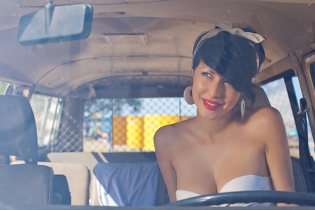 a beautiful retro-looking girl with blue eyes and red lips is looking into the rear view mirrorの写真素材