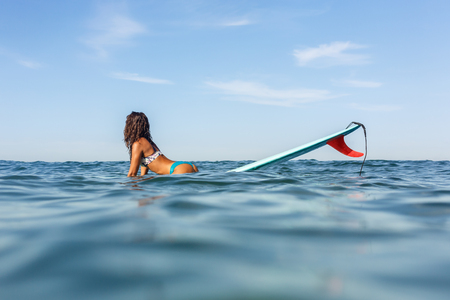 Beautiful surfing girl in sexy bikini sit on a front of big longboard surfboard board so we see one...