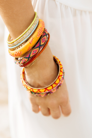 Close up of a woman hand with lot of bracelet, wristband, band, bangle, armlet on white summer...