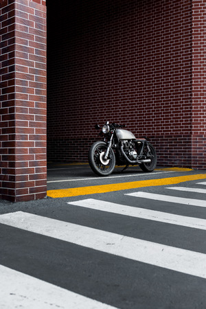 Old motorbike parking near brick wall of finance building. Everything is ready for having fun driving the empty road on a motorcycle tour journey. City hobby. Space for your individual text.の写真素材