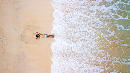 Aerial view of young sporty lady in blue sexy bikini. Hot beach with cool waves. Summer and holiday...