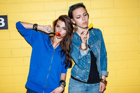 Lifestyle portrait of two beautiful best friends hipster woman wearing stylish bright outfits and...