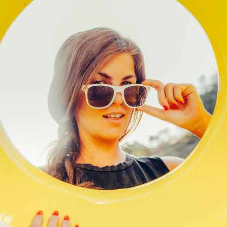 Close up portrait of a beautiful sporty woman in shirt correct her sunglasses and smile through big...