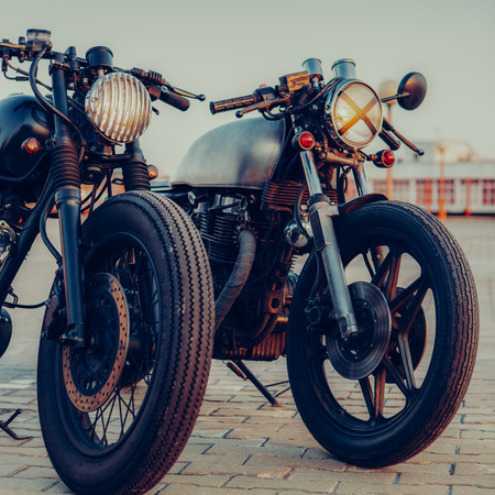 Two vintage custom motorcycle caferacer one with grill headlight another with tape cross over optic...