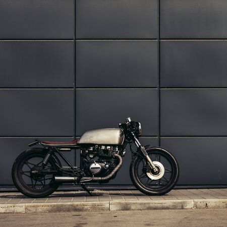 Craft motorbike parking near gray wall of industrial building. Everything is ready for having fun driving the empty road on a motorcycle tour journey. Man hobby. Space for your individual text.の写真素材