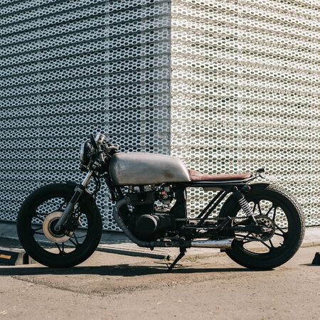 Craft motorcycle parking near wall of finance building. Everything is ready for having fun driving the empty road on a motorcycle tour journey. Businessman hobby. Space for your individual text.の写真素材