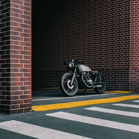 Old motorbike parking near brick wall of finance building. Everything is ready for having fun driving the empty road on a motorcycle tour journey. City hobby. Space for your individual text.の写真素材