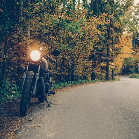 Silver old caferacer motorcycle parking on a country road. Everything is ready for having fun driving the empty road on a motorcycle tour journey. Modern hipster hobby. Space for your individual text.の写真素材