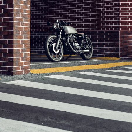 Old motorcyle parking near brick wall of industrial building. Everything is ready for having fun after hard day in office. Businessman city hipster hobby. Space for your individual text.の写真素材
