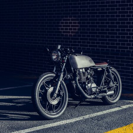 Custom motorbike parking near brick wall of finance building. Everything is ready for having fun after hard day in office. Businessman city hipster hobby. Space for your individual text.の写真素材