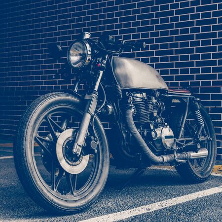 Old motorcycle parking near brick wall of finance building. Everything is ready for having fun driving the empty road on a motorcycle tour journey. City hobby. Space for your individual text.の写真素材