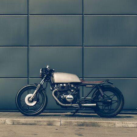 Custom motorbike parking near gray wall of industrial building. Everything is ready for having fun driving the empty road on a motorcycle tour journey. Man hobby. Space for your individual text.の写真素材