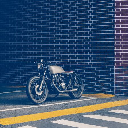 Handmade motorbike parking near brick wall of industrial building. Everything is ready for having...