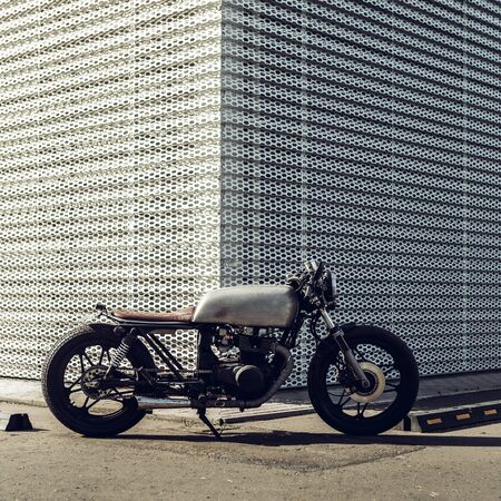 Old motorcycle parking near wall of finance building. Everything is ready for having fun driving the empty road on a motorcycle tour journey. Businessman hobby. Space for your individual text.の写真素材
