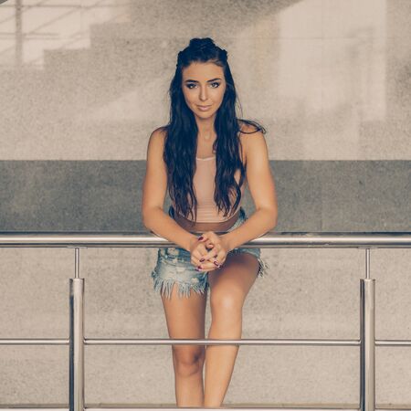 Portrait of athletic young lady in denim shorts, pink top and fashion hair style smiling and have good time in summer city. Urban style, healthy girl lifestyle and sport concept. Hipster city life.の写真素材