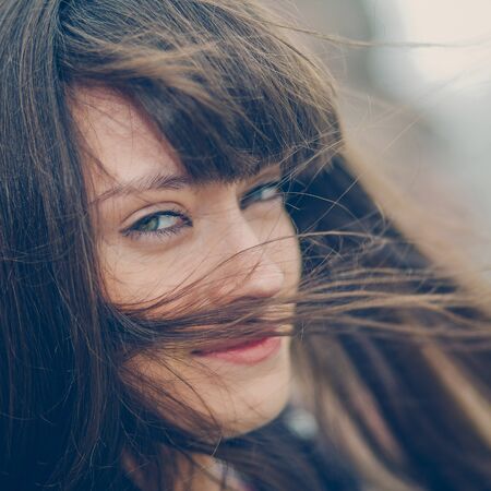 A beautiful girl with long hair coquettishly smiling. Young modern city woman look to the camera. Urban lifestyle holidays.の写真素材