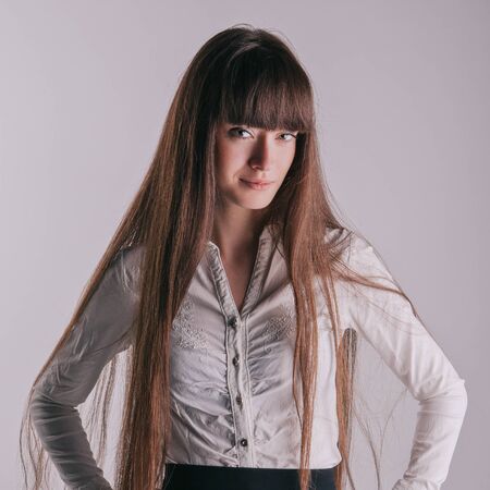 A beautiful girl with long hair coquettishly smiling. Young modern city woman look to the camera. Urban lifestyle holidays.の写真素材