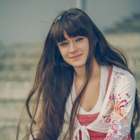 A beautiful girl with long hair coquettishly smiling. Young modern city woman look to the camera. Urban lifestyle holidays.の写真素材