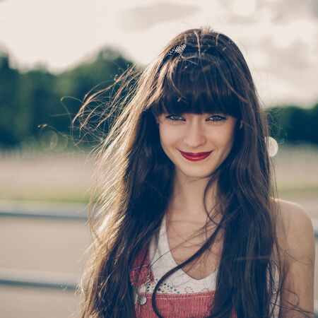 A beautiful girl with long hair coquettishly smiling. Young modern city woman look to the camera. Urban lifestyle holidays.の写真素材