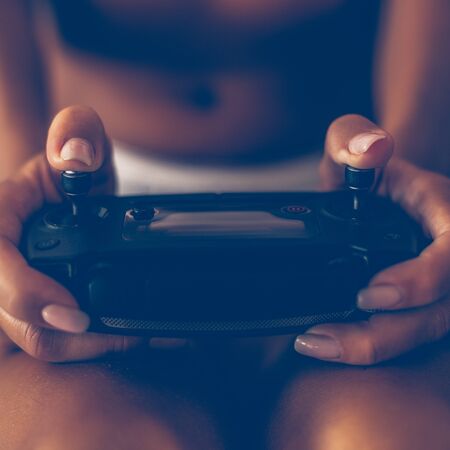 Closeup of a woman hands use sticks of remote controller from modern AI drone. Sexy lady in lingerie...