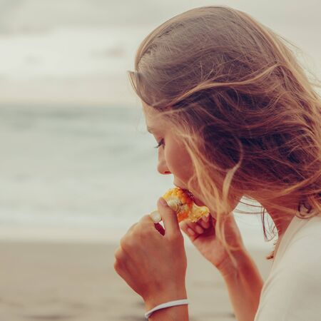 Healthy diet. Vegetarian hipster woman eat fresh organic grilled corn. Sporty lady on sea beach...