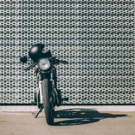 Vintage motorcycle parking near wall of finance building. Everything is ready for having fun driving the empty road on a motorcycle tour journey. Modern man hobby. Space for your individual text.の写真素材