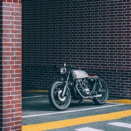 Old motorbike parking near brick wall of industrial building. Everything is ready for having fun after hard day in office. Businessman city hipster hobby. Space for your individual text.の写真素材