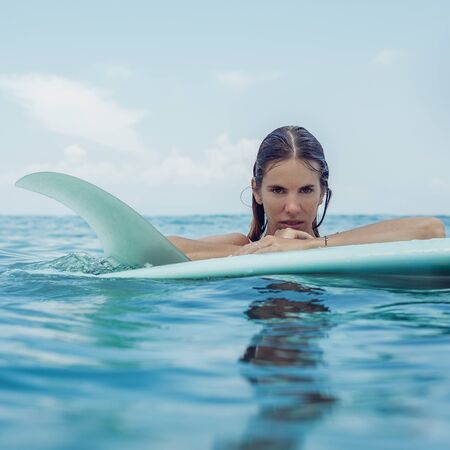 Beautiful young fit surfer woman in sexy pink bikini with single fin surf longboard. Girl have fun during hot summer day at tropic island resort, relax vacation concept. Hipster lifestyle advertising.の写真素材