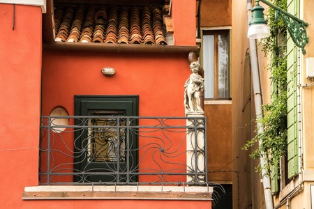 Venice, Italy - September 07, 2017: A picturesque Venetian house with a statue of a little angel. Red house, Venice, details.のeditorial素材