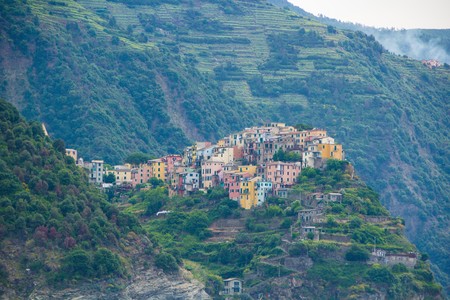 The town of Corniglia, one of the five small towns in the Cinque Terre national Park, Italy. View from the excursion ship. Amazing colorful small town located in the mountains near the sea.の写真素材