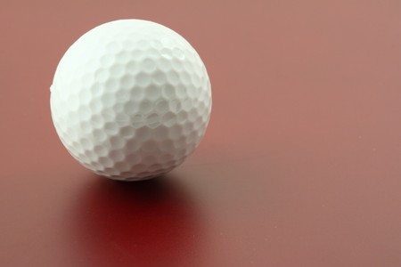 golf ball on red surfaceの写真素材