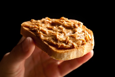 peanut butter toast bread in hand on black backgroundの写真素材