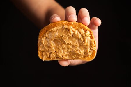 peanut butter toast bread in hand on black backgroundの写真素材