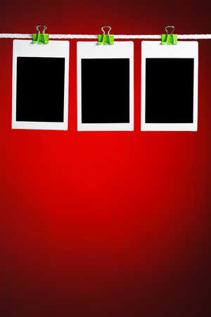 blank photos hanging on rope, red backgroundの写真素材