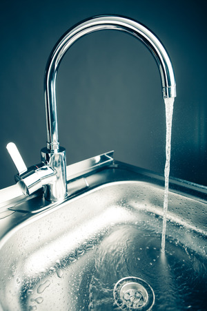 mixer tap with flowing water, blue toneの写真素材