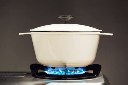 white cast iron saucepan on the gas stoveの写真素材