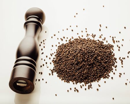 pepper mill and peppercorns heap, white backgroundの写真素材